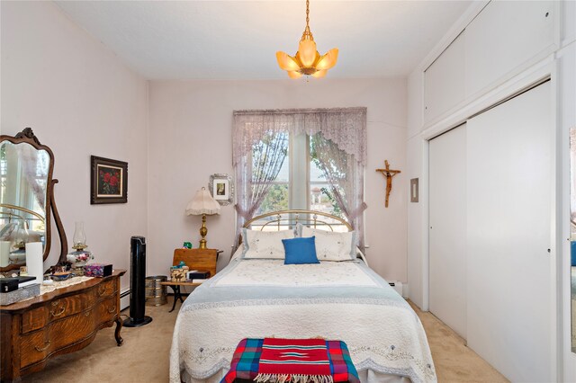 bedroom featuring a chandelier, a closet, light colored carpet, and a baseboard heating unit