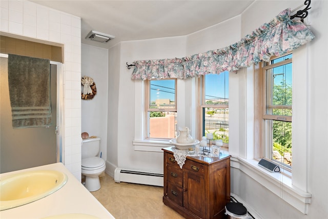 bathroom featuring toilet, baseboard heating, and a healthy amount of sunlight