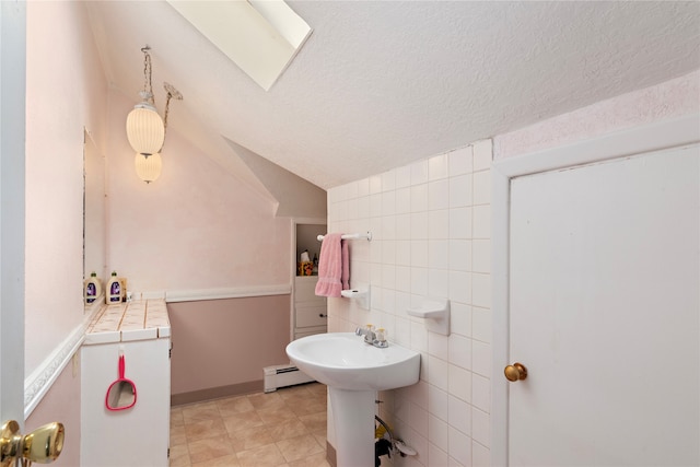 bathroom featuring tile patterned floors, a textured ceiling, vaulted ceiling, a baseboard radiator, and tile walls