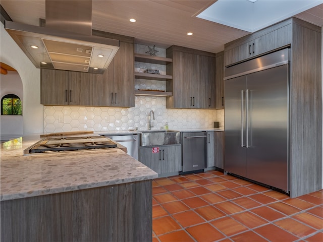 kitchen featuring tasteful backsplash, stainless steel appliances, light stone countertops, dark tile flooring, and sink