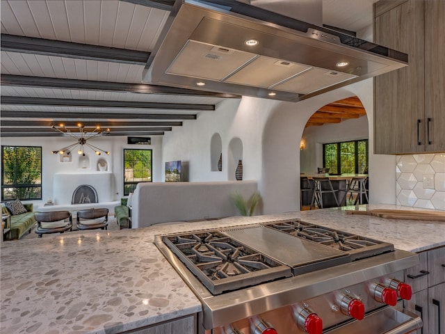 kitchen featuring high end stove, tasteful backsplash, beamed ceiling, a notable chandelier, and light stone countertops