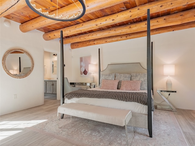 bedroom with beam ceiling, light wood-type flooring, wood ceiling, and ensuite bathroom