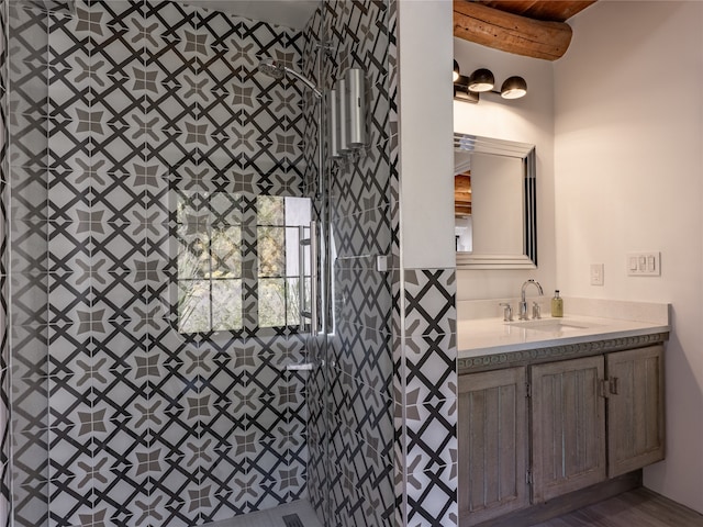 bathroom with a tile shower, oversized vanity, and hardwood / wood-style flooring