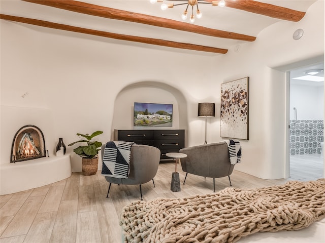 living area featuring an inviting chandelier, beam ceiling, and light wood-type flooring