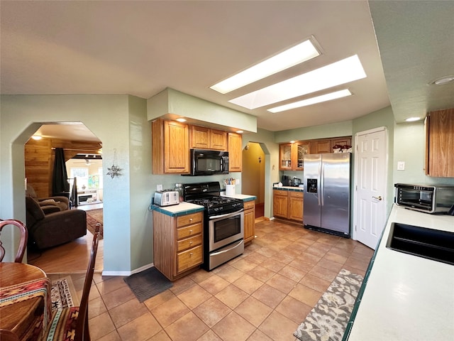 kitchen featuring light tile patterned flooring, stainless steel appliances, sink, and a skylight