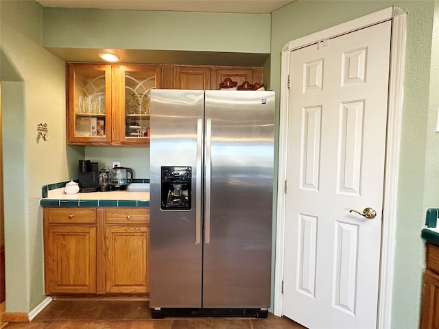 kitchen featuring stainless steel fridge with ice dispenser, tile counters, and dark tile patterned floors