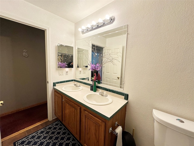 bathroom featuring tile patterned floors, dual bowl vanity, and toilet