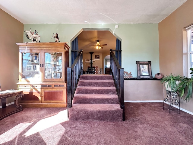 stairs featuring ceiling fan, a textured ceiling, and carpet