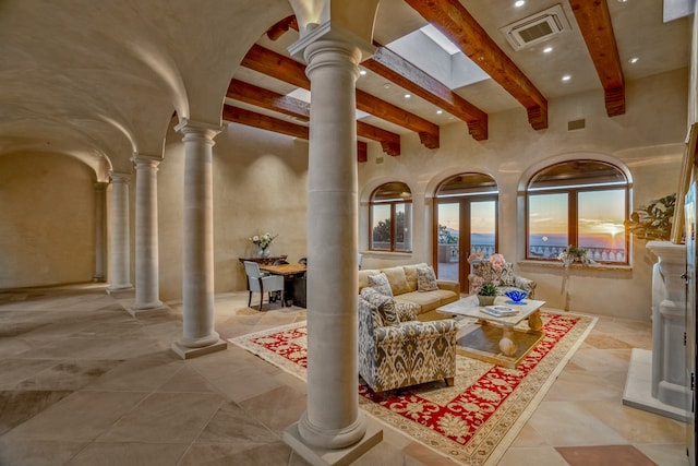 living room with beamed ceiling, light tile floors, and decorative columns