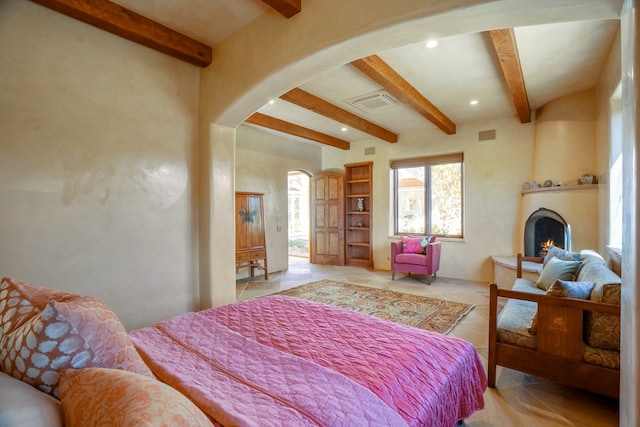 bedroom featuring beam ceiling, a fireplace, and light tile floors