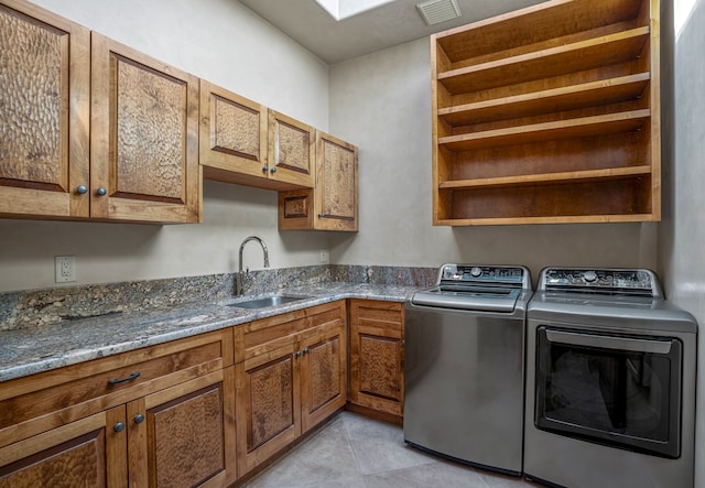 laundry area with light tile flooring, cabinets, separate washer and dryer, and sink