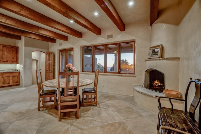 dining room featuring light tile floors and beamed ceiling