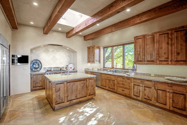 kitchen featuring light stone counters, stainless steel dishwasher, an island with sink, light tile floors, and sink