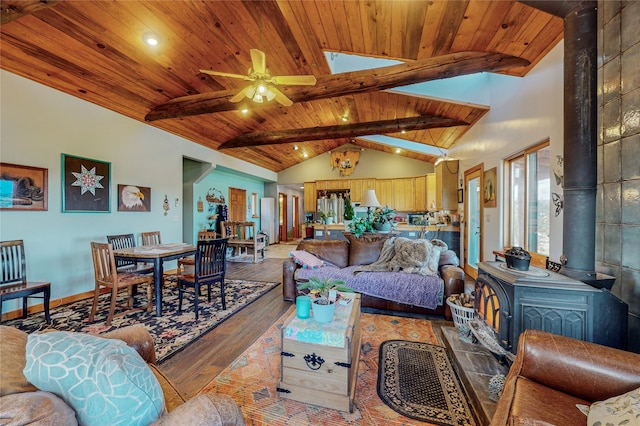 living room featuring ceiling fan, wood-type flooring, wood ceiling, a wood stove, and vaulted ceiling with skylight