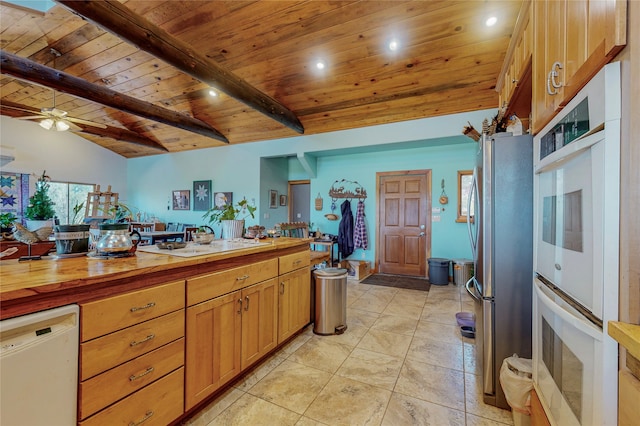 kitchen featuring ceiling fan, vaulted ceiling with beams, stainless steel refrigerator, light tile flooring, and dishwasher