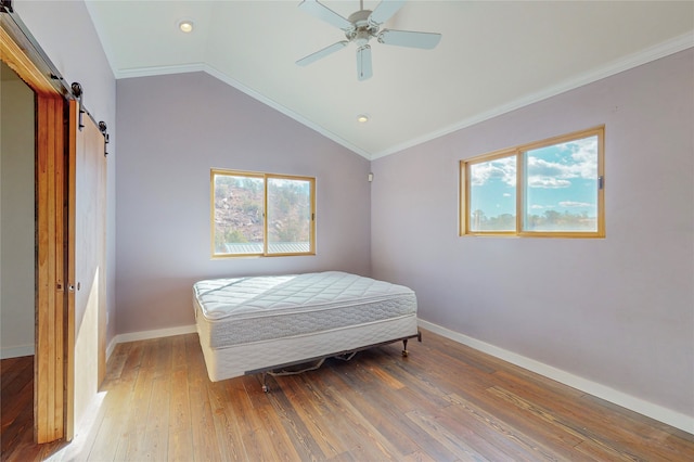 bedroom featuring wood-type flooring, ornamental molding, and a barn door