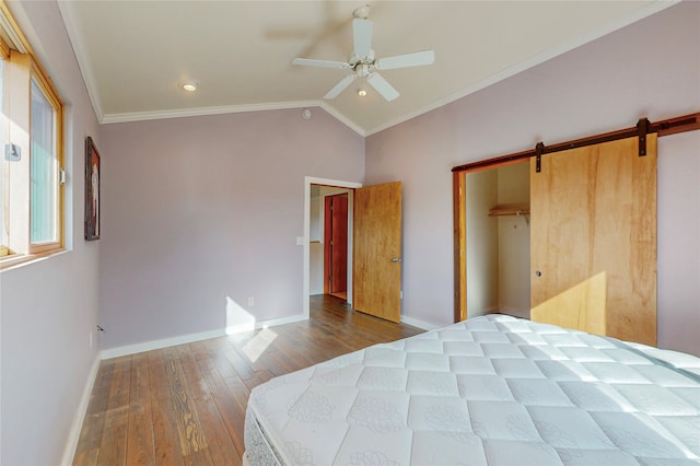 bedroom with crown molding, a barn door, and dark wood-type flooring