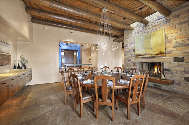 dining space with a stone fireplace, wooden ceiling, and beam ceiling