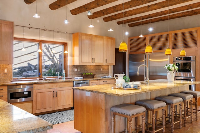 kitchen featuring decorative backsplash, appliances with stainless steel finishes, a kitchen island with sink, and sink