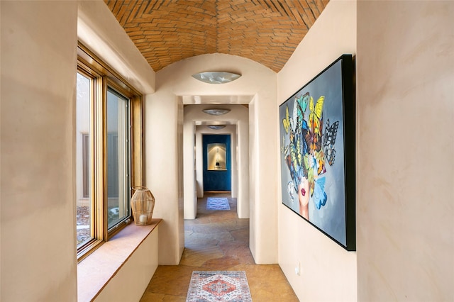 hall featuring brick ceiling, lofted ceiling, tile patterned flooring, and plenty of natural light