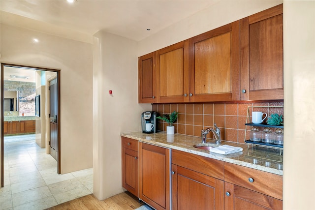 kitchen featuring backsplash, light hardwood / wood-style floors, light stone countertops, and sink