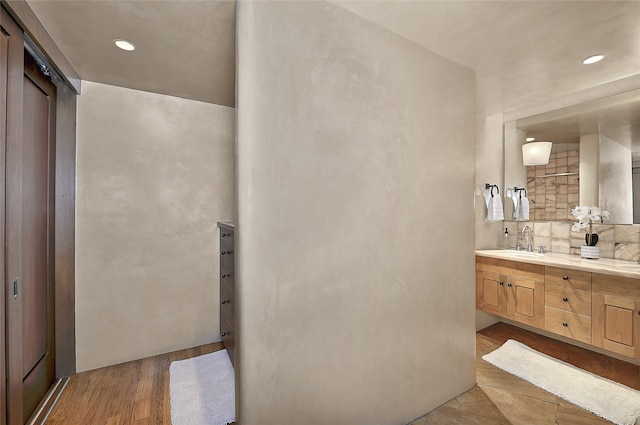 bathroom featuring vanity, decorative backsplash, and hardwood / wood-style flooring