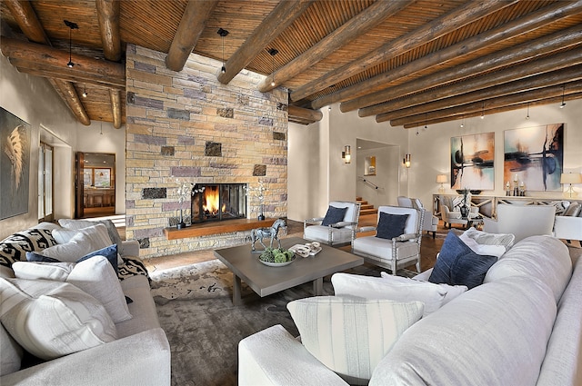 living room with a high ceiling, hardwood / wood-style floors, beam ceiling, a stone fireplace, and wood ceiling