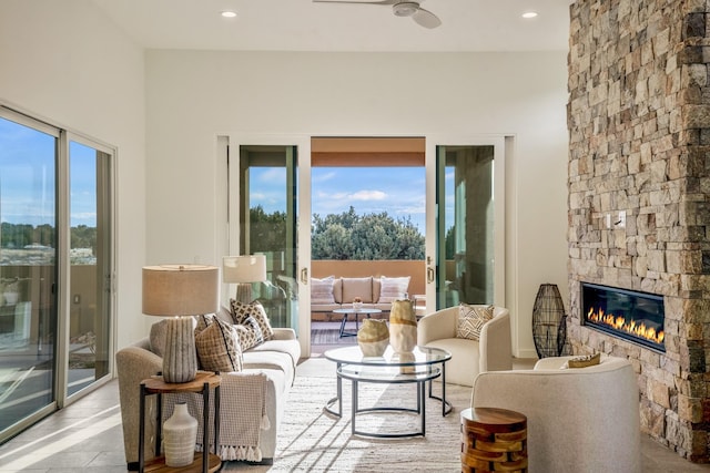 living room with ceiling fan, light tile patterned floors, and a stone fireplace