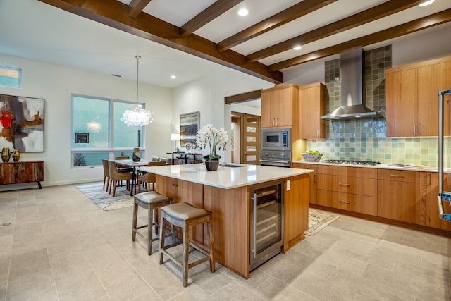 kitchen with beverage cooler, stainless steel appliances, a center island, wall chimney exhaust hood, and decorative light fixtures