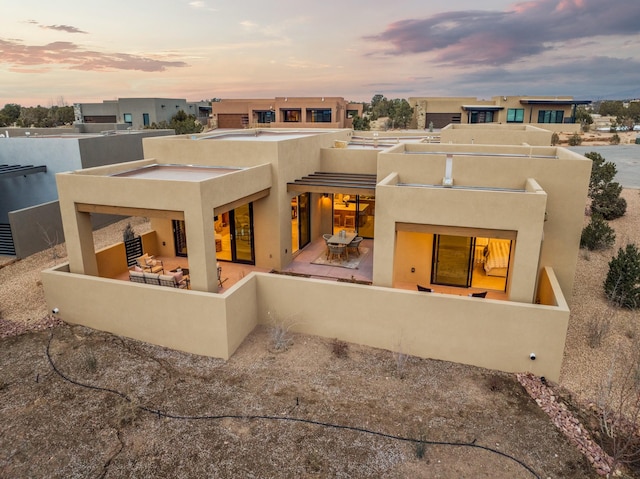 back house at dusk with a patio area