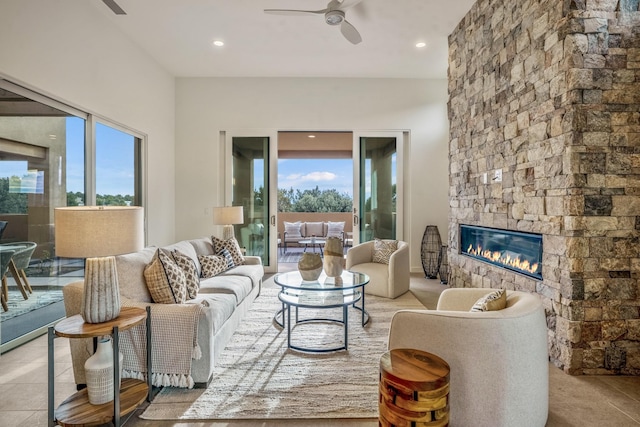 tiled living room with ceiling fan and a stone fireplace