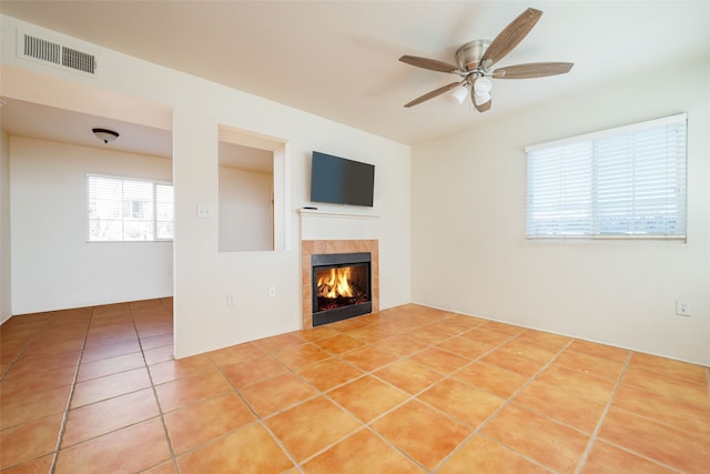 unfurnished living room with tile flooring, a tile fireplace, and ceiling fan