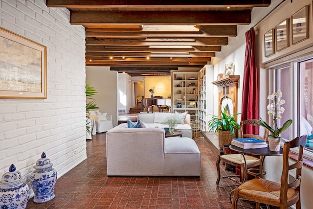 living room featuring beam ceiling, brick wall, and a wealth of natural light