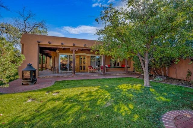 rear view of property with a yard, ceiling fan, and a patio area