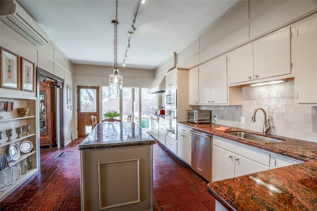 kitchen with an AC wall unit, white cabinetry, backsplash, appliances with stainless steel finishes, and sink