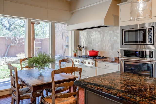 kitchen with tasteful backsplash, stainless steel appliances, custom exhaust hood, and white cabinetry