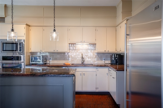 kitchen featuring white cabinets, appliances with stainless steel finishes, dark stone countertops, and sink