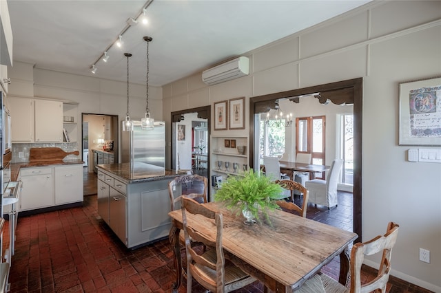 dining area with rail lighting, an AC wall unit, and a chandelier