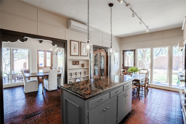 kitchen featuring decorative light fixtures, gray cabinets, a kitchen island, and an inviting chandelier