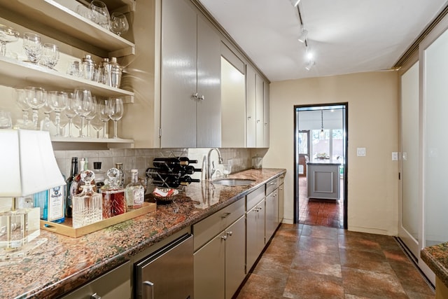 kitchen featuring backsplash, dark tile floors, sink, dark stone counters, and rail lighting