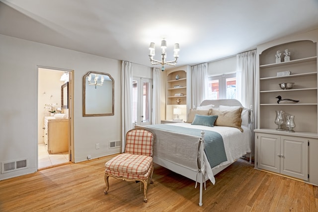 bedroom featuring a notable chandelier, light hardwood / wood-style flooring, and ensuite bath