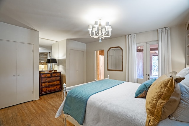 bedroom featuring a notable chandelier, multiple closets, french doors, and light hardwood / wood-style flooring