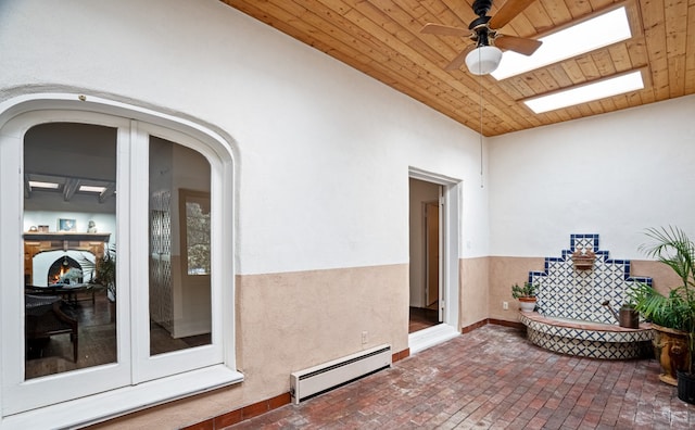 view of exterior entry featuring ceiling fan, a baseboard radiator, a patio area, and french doors