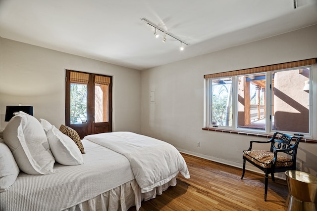 bedroom with track lighting and light wood-type flooring