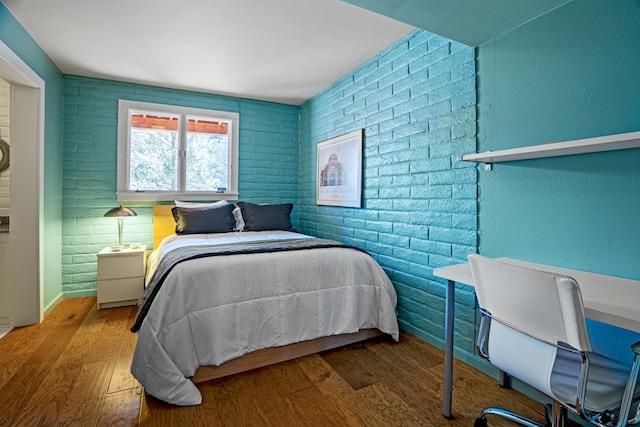 bedroom featuring hardwood / wood-style floors and brick wall