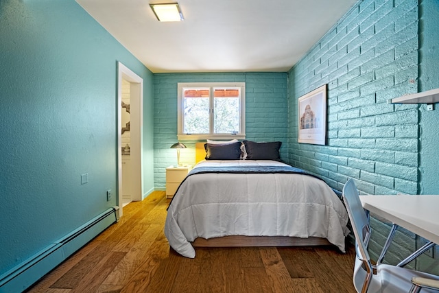 bedroom featuring brick wall, a baseboard radiator, and hardwood / wood-style flooring