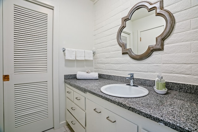 bathroom with brick wall and vanity with extensive cabinet space