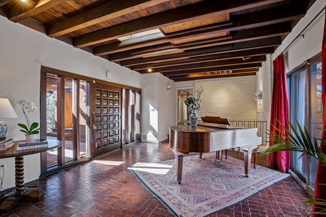 interior space featuring brick wall, a skylight, wooden ceiling, and beamed ceiling