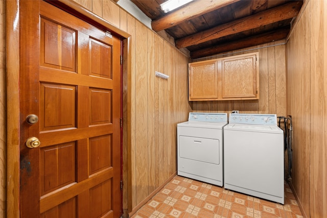 washroom with wood walls, cabinets, light tile flooring, and washer and dryer