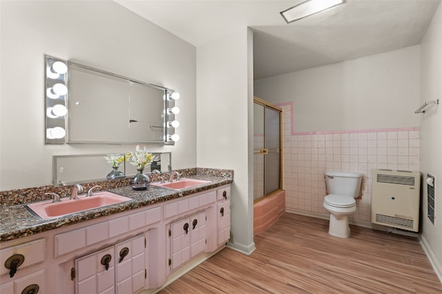 full bathroom featuring double sink, hardwood / wood-style floors, tile walls, vanity with extensive cabinet space, and toilet